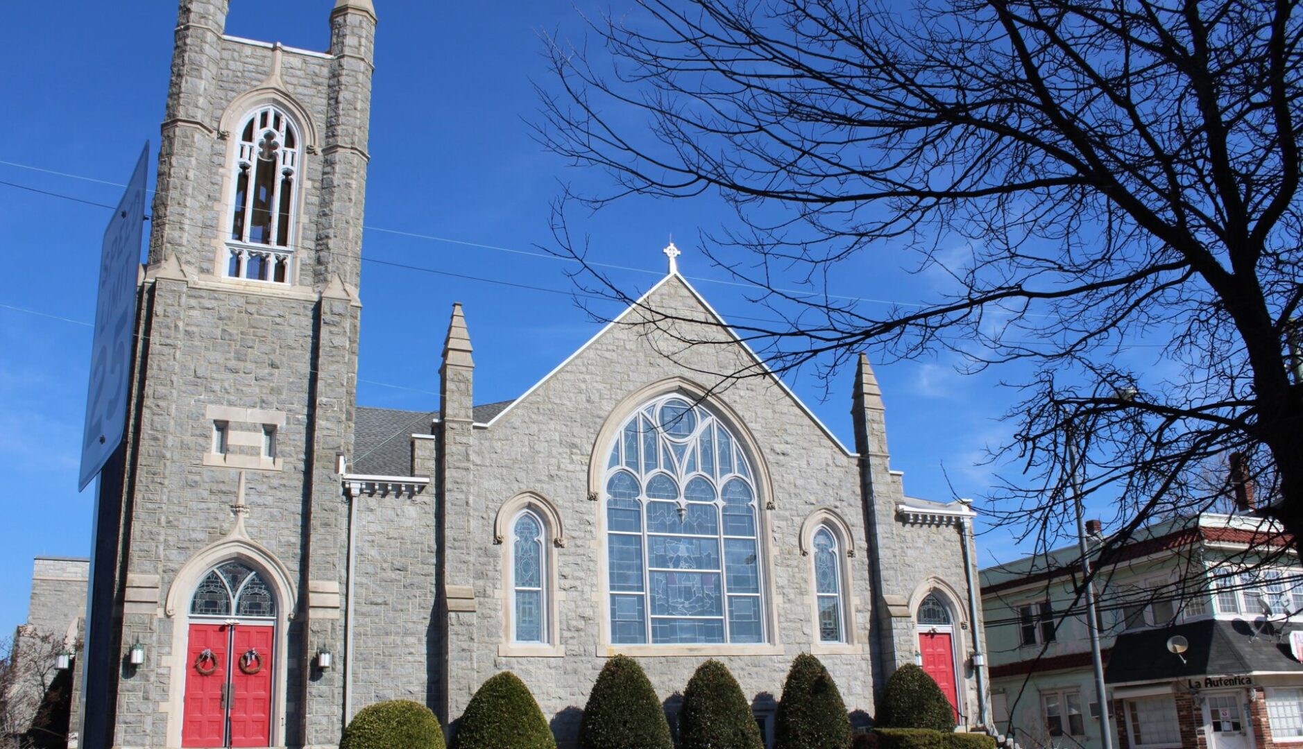 A church with a large window and trees in front of it.